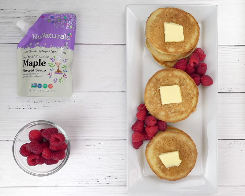Three stacks of keto pancakes with NuNaturals Maple Flavored Syrup and rasperries