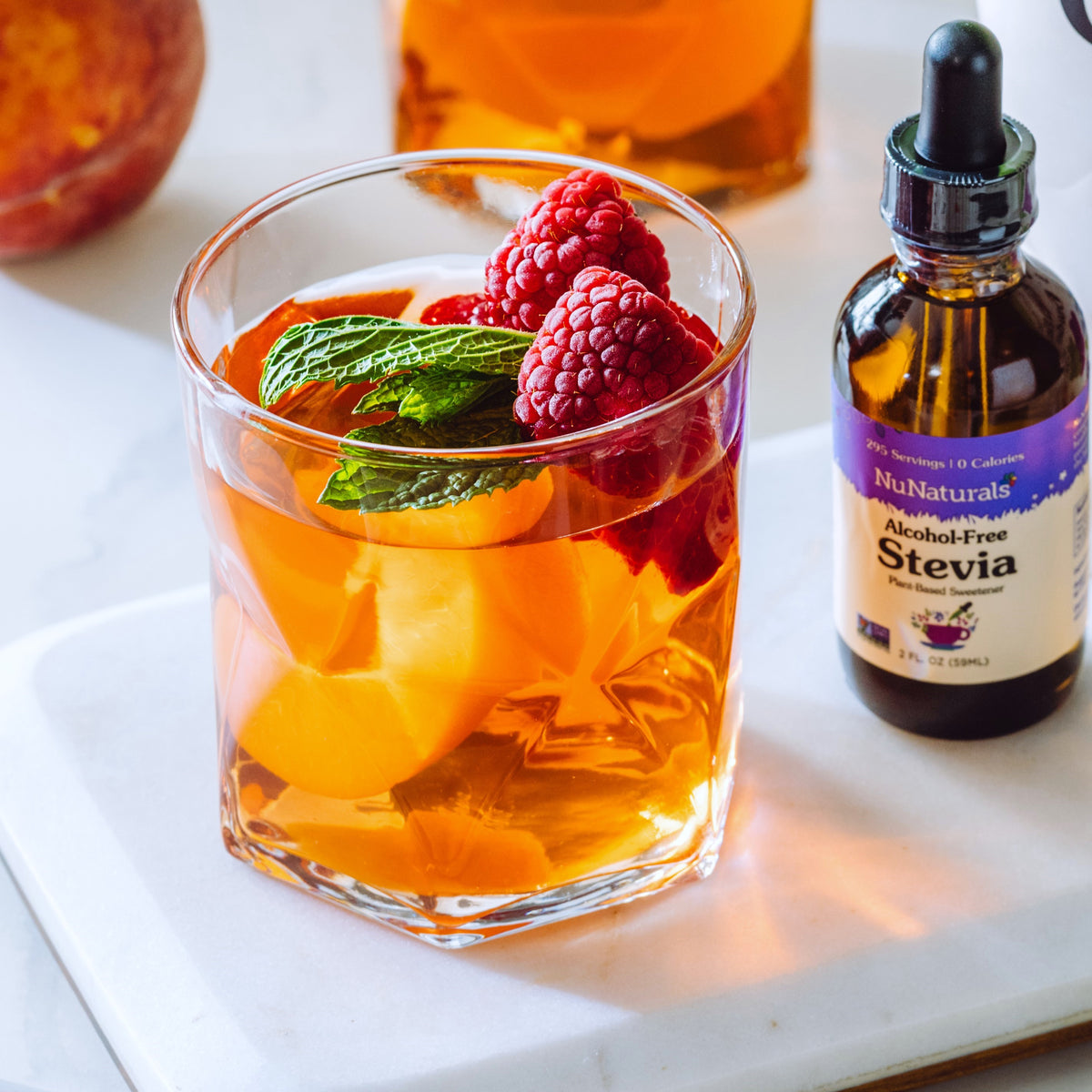 Alcohol-Free Stevia 2 oz dropper bottle beside a glass of peach and raspberry drink with a mint leaf