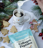 Collagen Peptides pouch at the bottom of the frame as powder is poured into a snowman mug, with cookies and pine branches