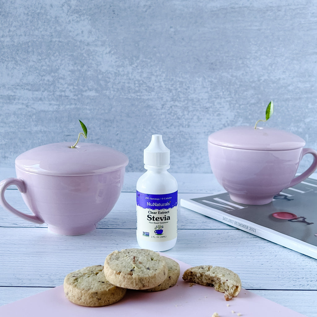 Clear Extract Stevia 2 oz dropper bottle between two lavender lidded cups, with shortbread cookies in front