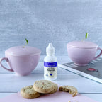 Clear Extract Stevia 2 oz dropper bottle between two lavender lidded cups, with shortbread cookies in front