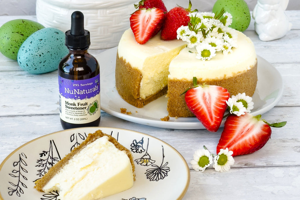 Monk Fruit Sweetener 2 oz dropper bottle beside a cheesecake topped with strawberries and daisies, with speckled eggs