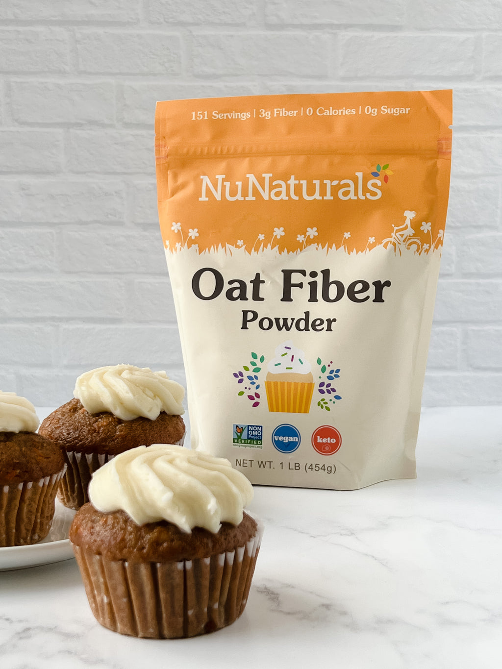 Oat Fiber pouch on a marble counter behind cupcakes topped with white frosting
