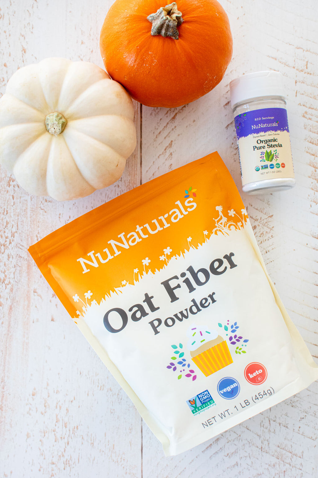 Oat Fiber pouch lying beside a white pumpkin, with a small pure stevia shaker at the top of the frame