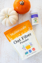 Oat Fiber pouch lying beside a white pumpkin, with a small pure stevia shaker at the top of the frame