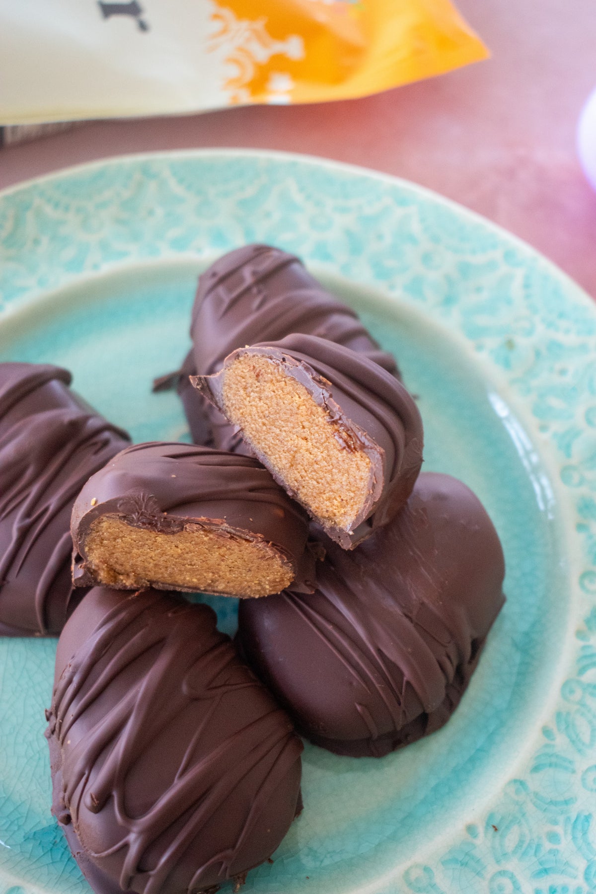 Chocolate-covered treats on a turquoise plate, one cut open to show the filling