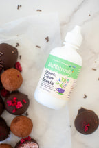 Organic Clear Extract Stevia 4 oz bottle lying on parchment paper beside chocolate truffles with raspberry pieces