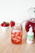 Organic Clear Extract Stevia 4 oz bottle beside a mason jar of pink iced drink with a strawberry and metal straw