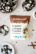 Organic Dutch Cocoa Powder pouch on a marble surface with chocolate crinkle cookies and a cinnamon stick