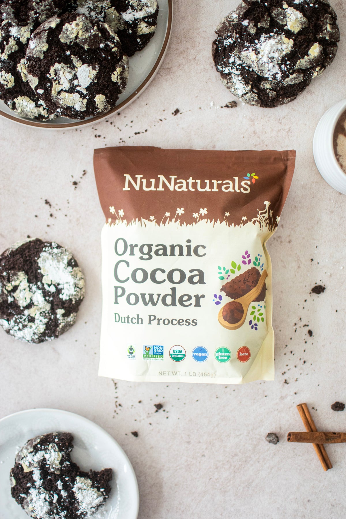 Organic Dutch Cocoa Powder pouch on a marble surface with chocolate crinkle cookies and a cinnamon stick