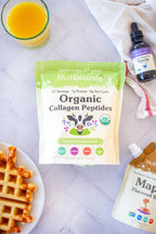 Organic Collagen pouch on a tile counter with a waffle, a vanilla stevia bottle and a syrup pouch at the edges