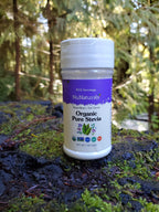 Organic Pure Stevia shaker sitting on a mossy log with evergreen trees in the background