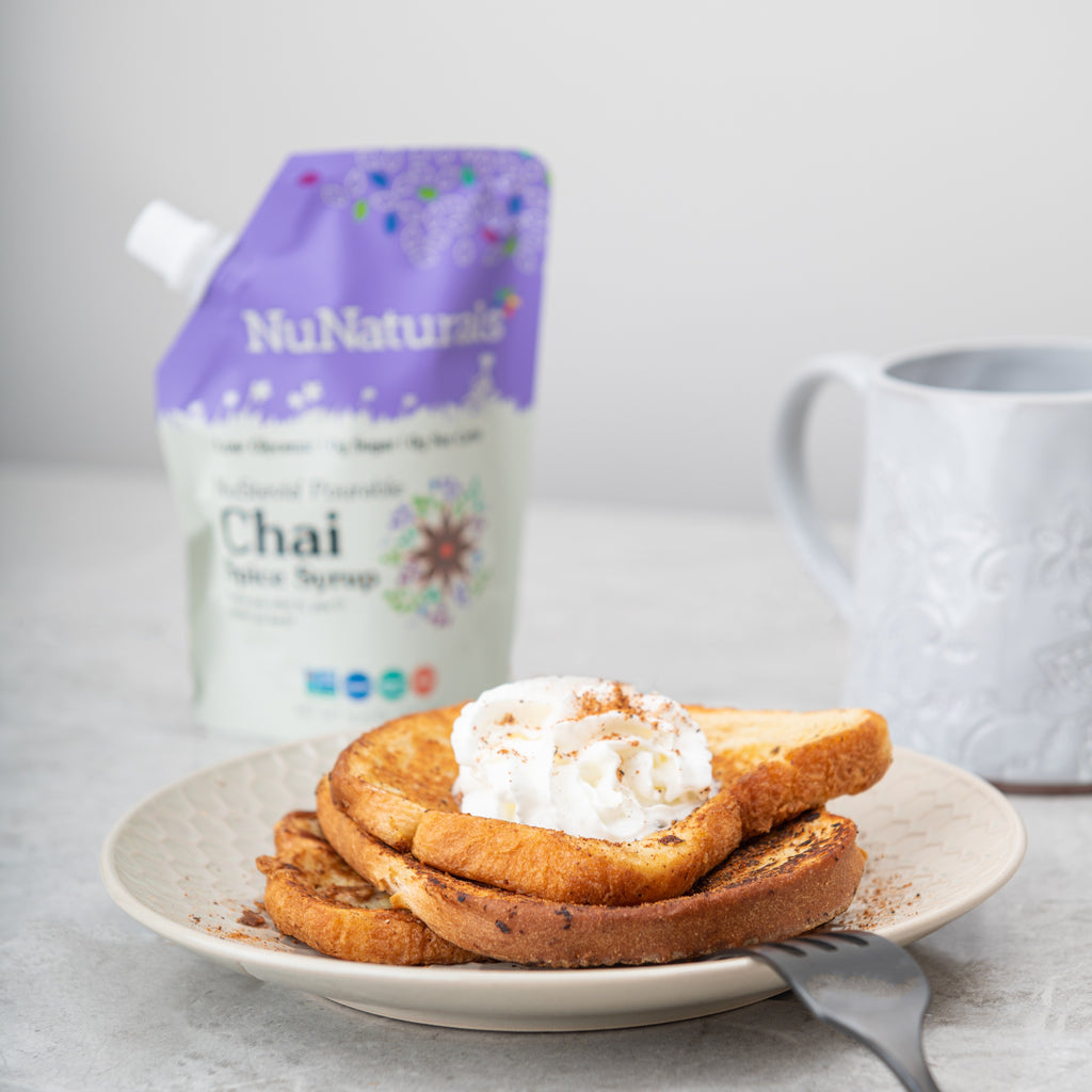 Chai Spice Syrup 6.6 oz pouch behind a plate of french toast topped with whipped cream, with a white mug