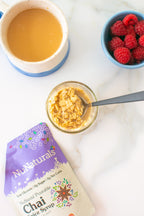 Purple NuNaturals pouch, partly cropped, beside a jar of oats with a spoon, a mug and a bowl of raspberries