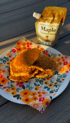 Maple Flavored Syrup 6.6 oz pouch at the top edge of the frame above a stack of pancakes on a floral plate