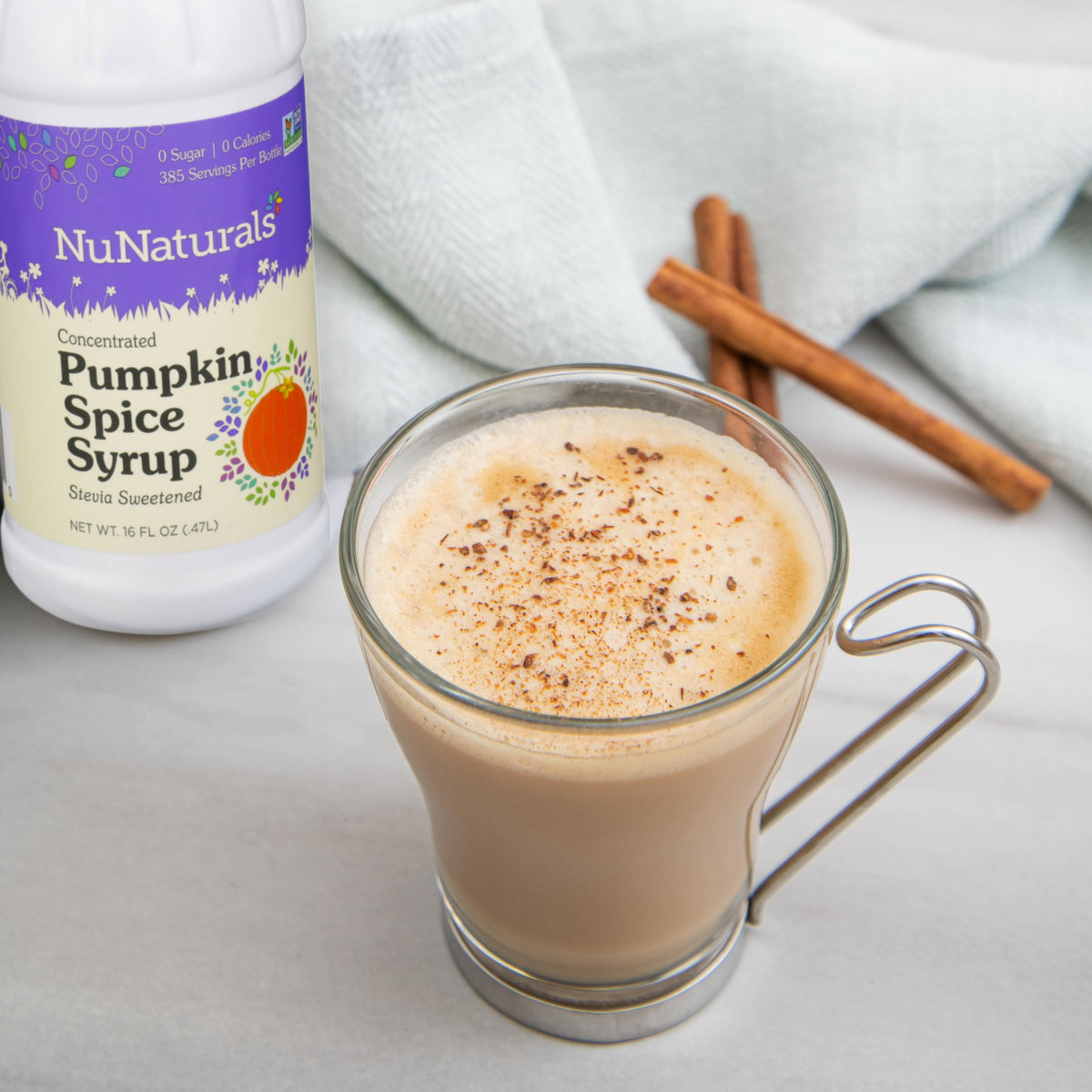 Pumpkin Spice Syrup 16 oz bottle label behind a glass mug of latte with cinnamon sticks nearby