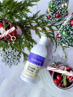 Simple Syrup 16 oz bottle lying on a table with evergreen sprigs, ornaments, cranberries, and candy cane stirrers