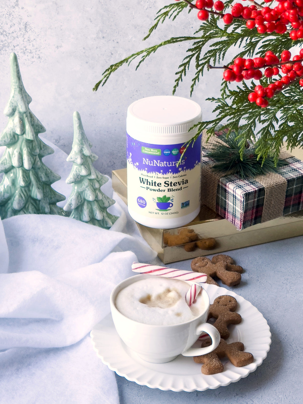 White Stevia Powder canister with holiday trees, a wrapped gift, gingerbread cookies and a cup of hot drink
