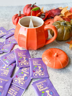 White Stevia Powder Blend Packets scattered on a table beside an orange pumpkin mug with a tea bag