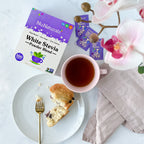 White Stevia Powder Blend Packets box and loose packets beside a cup of tea and a blueberry muffin on a plate