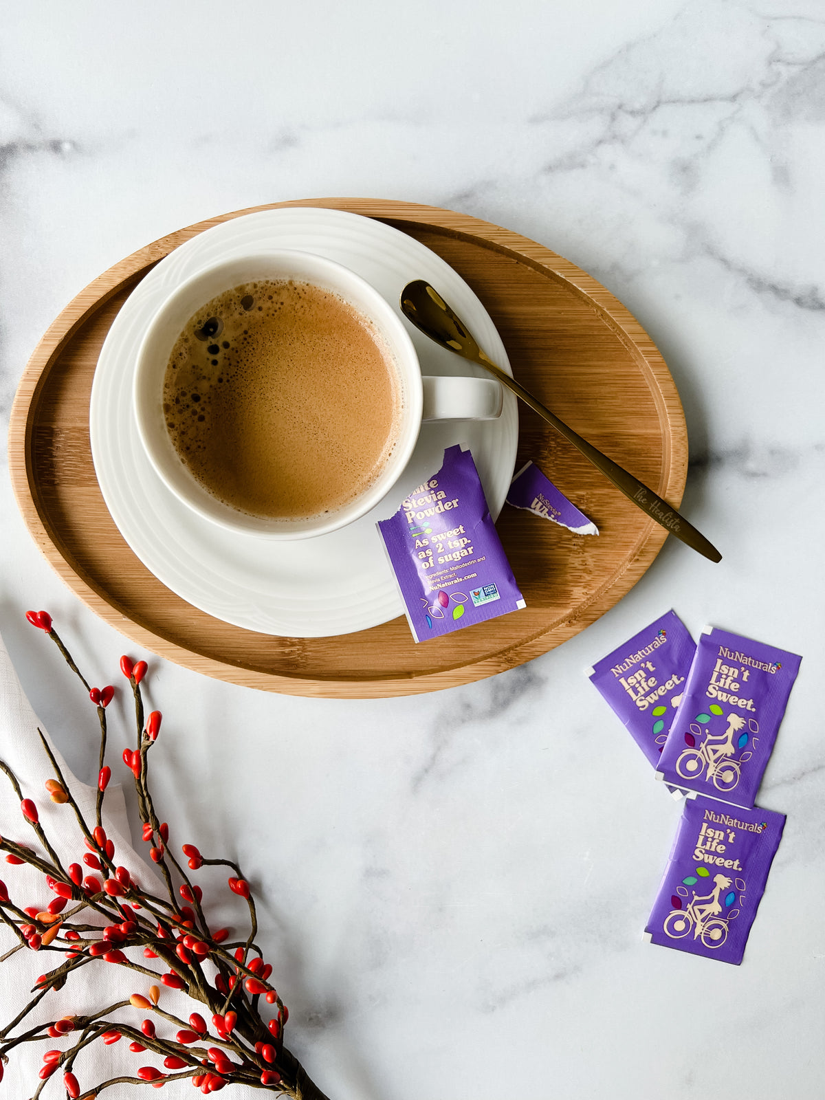 White Stevia Powder Blend Packets on a marble surface beside a cup of coffee on a wooden tray