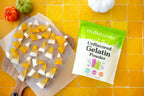 Unflavored Gelatin bag beside two-tone candy corn shaped gummies on parchment paper over yellow tile