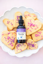 Vanilla Alcohol-Free Stevia 2 oz dropper bottle standing among heart-shaped cookies topped with purple sprinkles