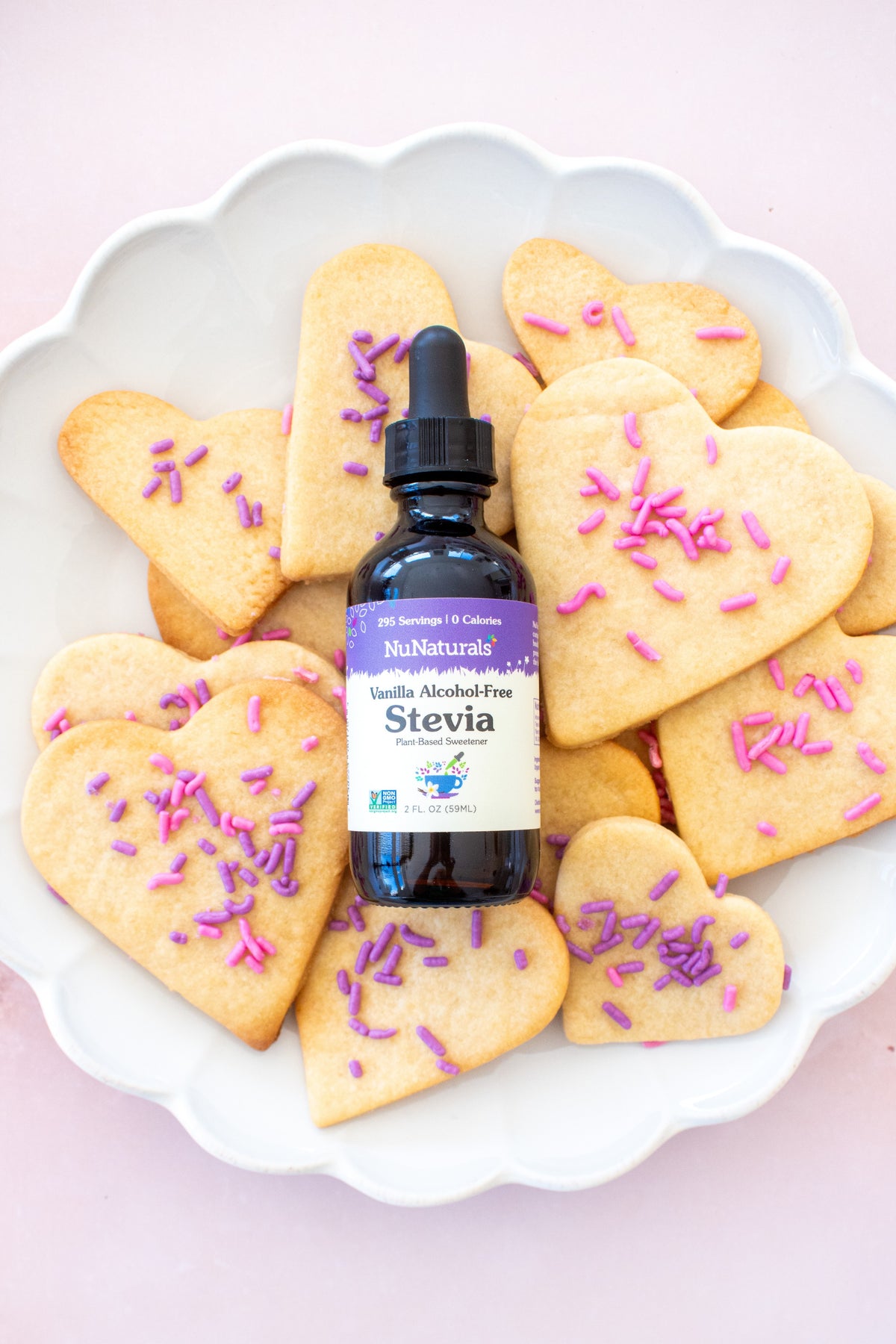 Vanilla Alcohol-Free Stevia 2 oz dropper bottle standing among heart-shaped cookies topped with purple sprinkles